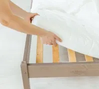 white hands putting sheet on bed